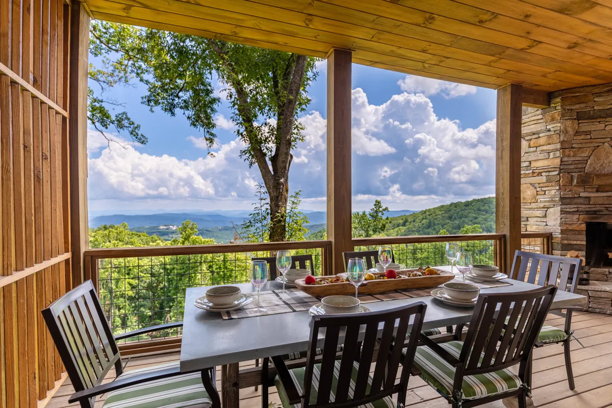 An exterior communal space featuring a cozy fire pit and inviting seating arranged for social gatherings, all set against a scenic mountain backdrop. String lights and the main building in the background suggest a welcoming atmosphere for both daytime and evening relaxation after outdoor adventures.