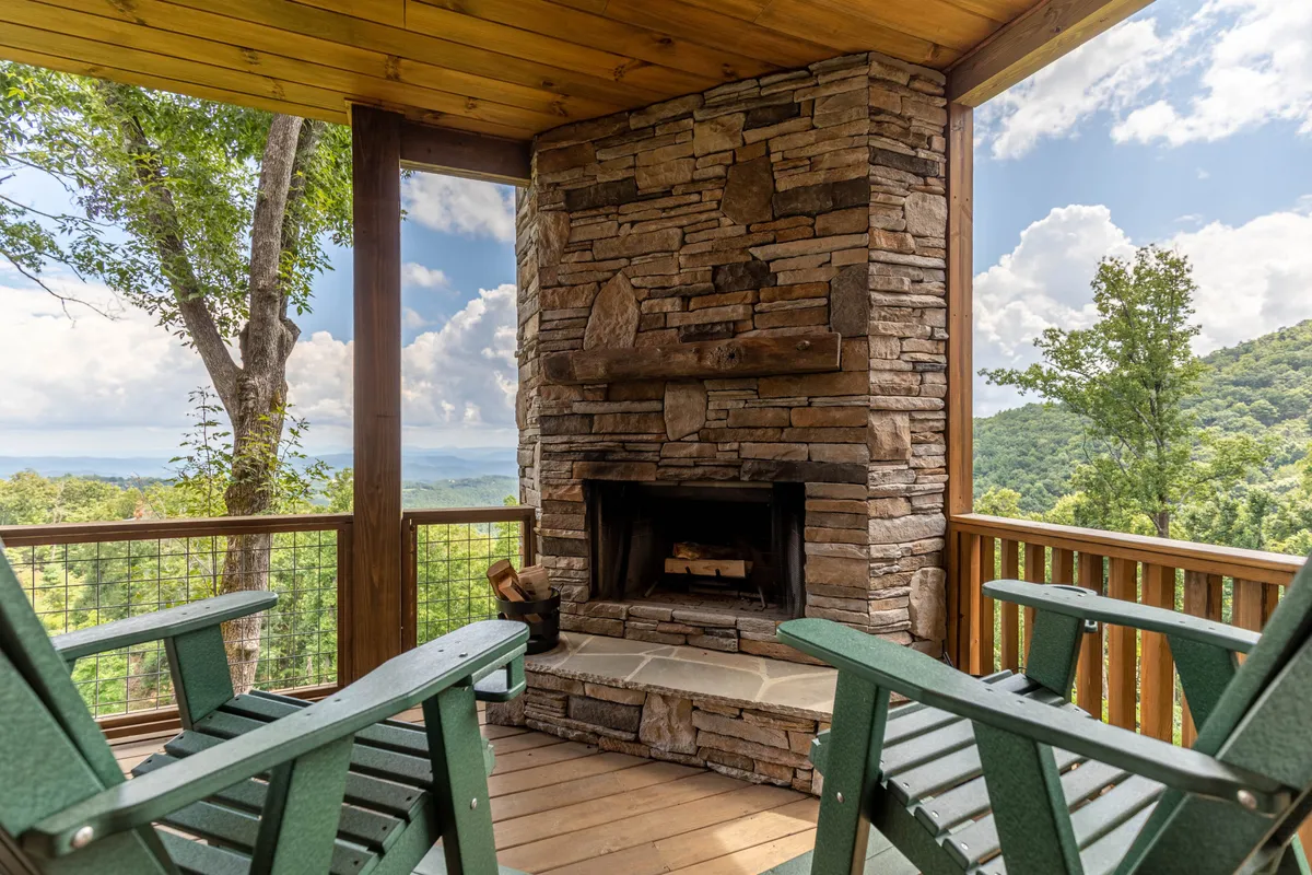An inviting exterior deck with a stone fireplace, green chairs, and beautiful mountain views in the background. The setup is perfect for enjoying morning coffee or unwinding while watching the sunset, echoing the peaceful deck moments described in the section.