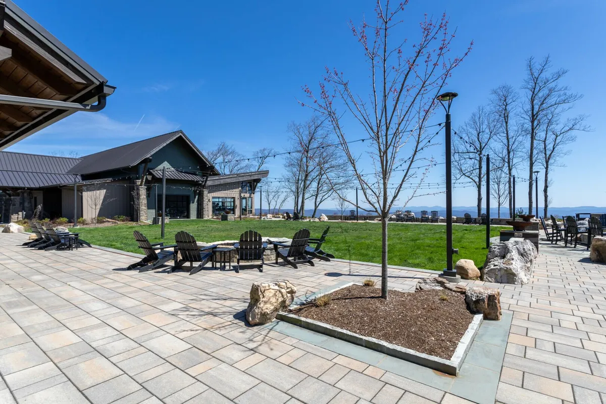 An outdoor patio space featuring a welcoming fire pit surrounded by comfortable seating, set against a backdrop of mountain views and open sky. The area exudes a tranquil ambiance perfect for relaxation or social gatherings.